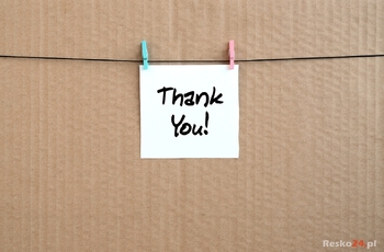 Thank you! Note is written on a white sticker that hangs with a clothespin on a rope on a background of brown cardboard