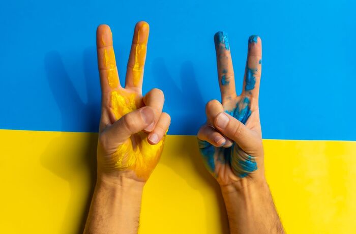 Stop war, conflict between Ukraine and Russia. A man wearing the colors of the Ukrainian flag and making the victory sign